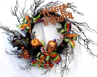 May include: A Halloween wreath with black branches, orange pumpkins, a skull, and green, orange, and black ribbon. The wreath has a sign that says "Happy Halloween".