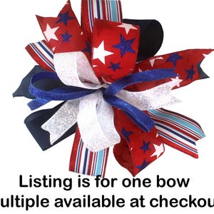 May include: A decorative bow featuring red, white, and blue ribbons. The bow has a patriotic theme with star and stripe patterns. The text "Listing is for one bow multiple available at checkout" is visible.