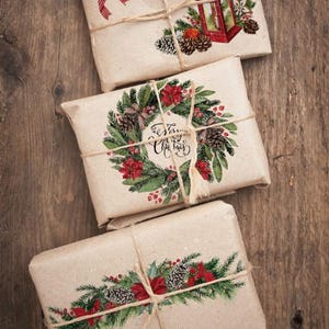 May include: Three wrapped gifts with festive Christmas designs. The top package features a red bow and a lantern illustration. The middle package has a wreath design with the text "Merry Christmas". The bottom package has a floral arrangement.