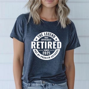 May include: A dark blue t-shirt with a white circle graphic that says "The Legend Has Officially Retired Since 2025 Not My Problem Anymore".