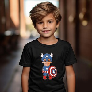 K&ouml;nnte beinhalten: Ein kleiner Junge tr&auml;gt ein schwarzes T-Shirt mit einem Comicbild von Captain America. Die Comicfigur hat das Gesicht des Jungen dar&uuml;bergelegt. Die Comicfigur tr&auml;gt ein blaues und rotes Kost&uuml;m mit einem rot-wei&szlig;-blauen Schild.