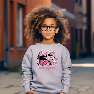 May include: A gray sweatshirt with a pink and black Minnie Mouse graphic. The graphic includes the number 5, the words "Name" and "Birthday Girl", and a pink bow.