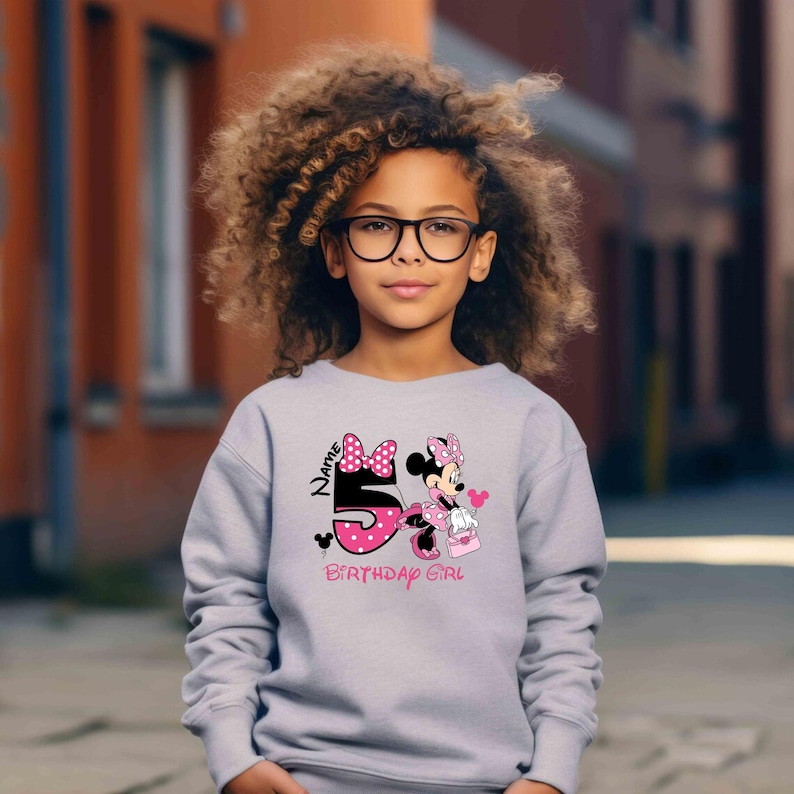 May include: A gray sweatshirt with a pink and black Minnie Mouse graphic. The graphic includes the number 5, the words "Name" and "Birthday Girl", and a pink bow.