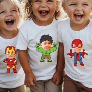 K&ouml;nnte beinhalten: Drei Kinder tragen wei&szlig;e T-Shirts mit aufgedruckten Gesichtern von Superhelden. Die Gesichter werden durch die Gesichter der Kinder ersetzt. Die Superhelden sind Iron Man, Hulk und Spiderman.