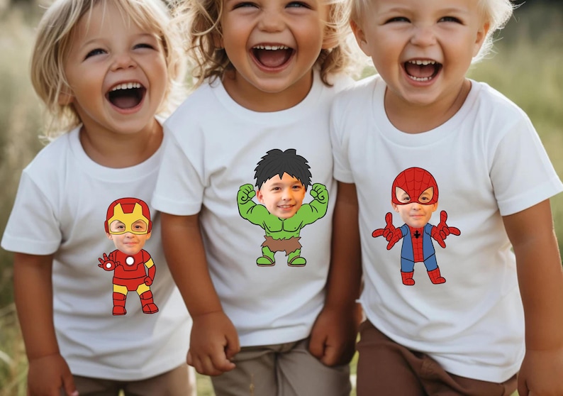 K&ouml;nnte beinhalten: Drei Kinder tragen wei&szlig;e T-Shirts mit aufgedruckten Gesichtern von Superhelden. Die Gesichter werden durch die Gesichter der Kinder ersetzt. Die Superhelden sind Iron Man, Hulk und Spiderman.