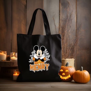 May include: Black canvas tote bag with a Mickey Mouse character dressed as a pumpkin. The bag has the name "HENRY" printed in orange dripping letters.