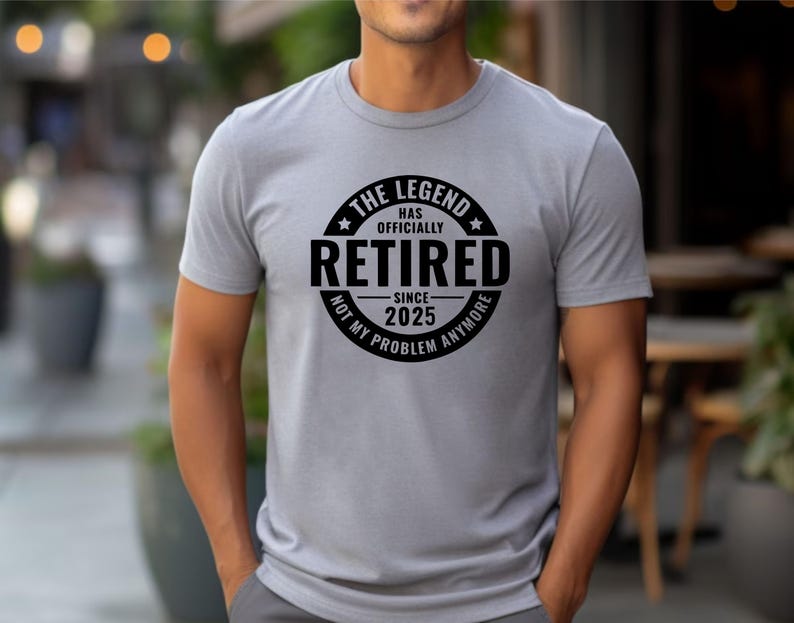 May include: A grey t-shirt with a black circle graphic that says "The Legend Has Officially Retired - Since 2025 - Not My Problem Anymore".