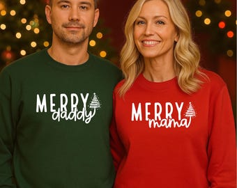 May include: A man and woman wearing matching Christmas sweaters. The man's sweater is dark green with the words "MERRY daddy" in white, and a Christmas tree graphic. The woman's sweater is red with "MERRY mama" in white, and a Christmas tree graphic.