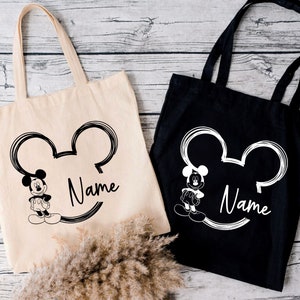 May include: Two tote bags with a black and white Mickey Mouse design. One bag is black with white text and the other is white with black text. Both bags have the word "Name" printed on them.