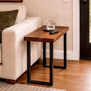 May include: A rectangular side table with a dark wood top and black metal legs. A glass of water and a remote control sit on the table. The table is next to a beige sofa with a green pillow.