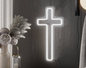 May include: A white neon cross is mounted on a dark gray wood-paneled wall. The cross is the focal point, emitting a soft glow. The scene includes a bedside table with a vase of flowers, a candle lantern, and a modern wall lamp.