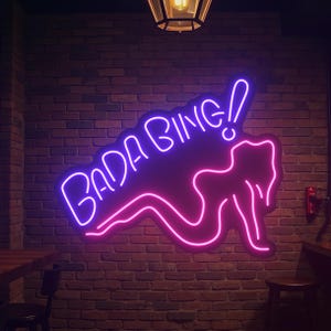 Bada Bing neon sign with bright LED glow in a retro style, perfect for bar decor, game rooms, man caves, or bedroom wall accents. Adds a fun and iconic pop culture vibe to any space.