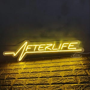 Afterlife LED neon sign for game room decor, bedroom wall art, or bar ambiance. This light-up sign captures a sleek cyberpunk aesthetic, making it an ideal gift for fans of Cyberpunk 2077 or modern sci-fi design. Perfect for man caves, gaming setups