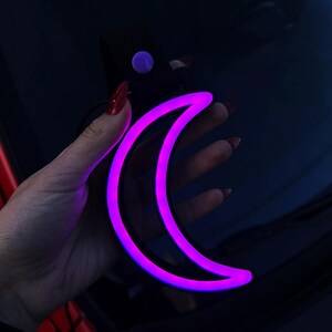Neon Moon Tsurikawa car handle decor styled in a cozy vehicle interior, perfect for night drivers, car guys, and unique decor lovers. Works beautifully in cars or rooms, adding a relaxing, dreamy glow that feels peaceful, aesthetic, and visually captivating.