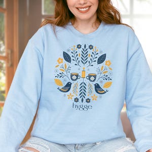 Scandinavian Hygge Sweatshirt – Cozy Folk Art Birds & Candle Design – Nordic Aesthetic Pullover for Winter Comfort Lovers