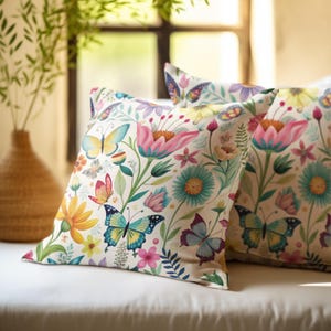 May include: Two decorative throw pillows with a white background and a colorful floral and butterfly pattern. The pillows are made of a soft, comfortable fabric and are perfect for adding a touch of whimsy to any room.