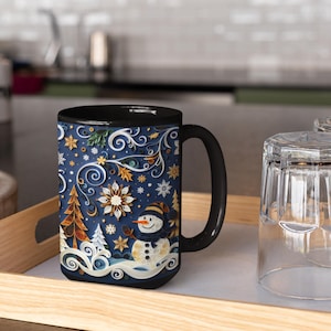 May include: A black-handled coffee mug with a winter-themed design. The mug features a snowman, snowflakes, and a Christmas tree on a dark blue background. The rim of the mug is black.