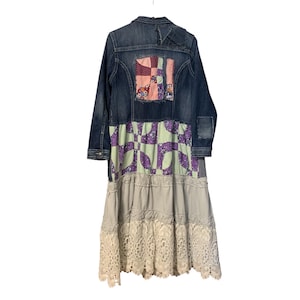 May include: A denim jacket with patchwork details and a long, tiered skirt. The jacket features a patchwork design on the back with pink, red, and floral fabrics. The skirt has a light purple and green pattern, with a cream lace hem.