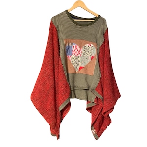 May include: A unique, olive green and red patchwork sweater with a heart design. The sweater features a textured, dotted pattern on the body and wide, flowing red sleeves. The heart is made of various fabric patches.