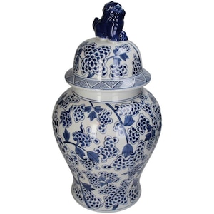 May include: A white and blue ceramic ginger jar with a lid. The jar is decorated with a blue grape vine pattern. A blue lion figurine sits atop the lid. The jar is a decorative home accent.
