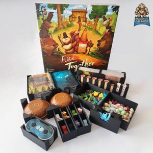 Puede incluir: Un inserto organizador negro para el juego de mesa Flock Together. El inserto incluye compartimentos para cartas, fichas y otros componentes del juego. El inserto se muestra con la caja del juego en el fondo.