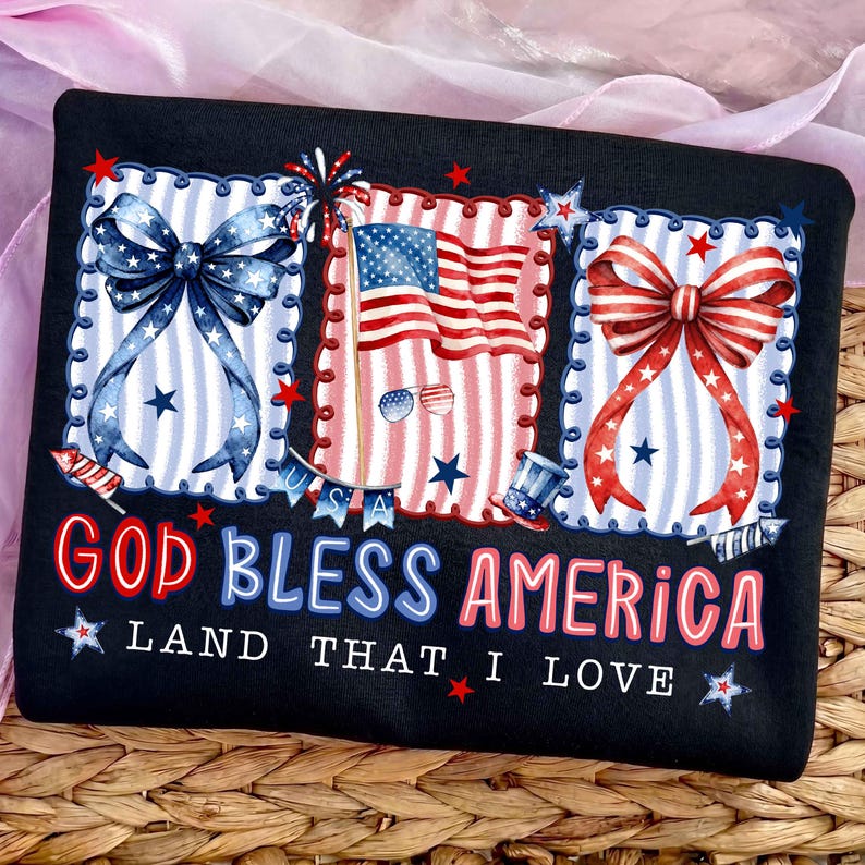 Puede incluir: Camiseta negra con un dise&ntilde;o patri&oacute;tico que presenta la bandera estadounidense, lazos y fuegos artificiales. El texto "GOD BLESS AMERICA LAND THAT I LOVE" se muestra en rojo y azul. Las estrellas y las rayas son prominentes.