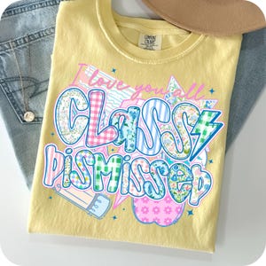 May include: Yellow t-shirt with a colorful patchwork design that says "I love you all Classy Dismissed".