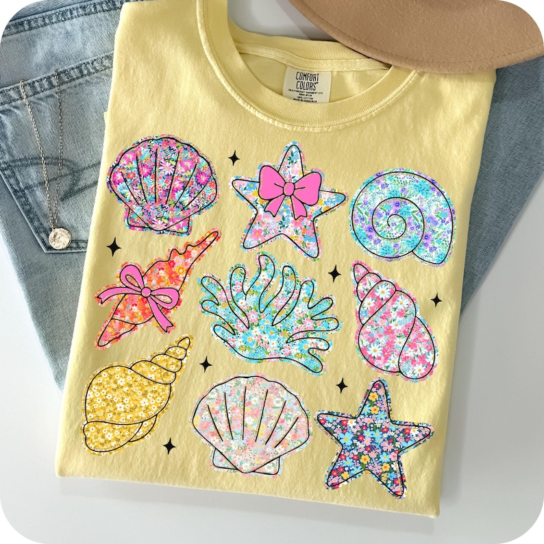May include: A yellow t-shirt with a floral print of seashells, starfish, and coral. The text "COMFORT COLORS" is visible on the shirt.
