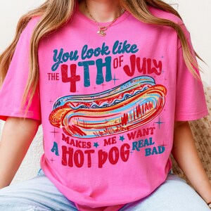 May include: Pink t-shirt with a graphic of a hot dog and the text "You look like the 4th of July makes me want a hot dog real bad." The design features red, blue, and yellow colors.