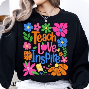 May include: Black sweatshirt with a colorful floral design and the text "Teach Love Inspire".