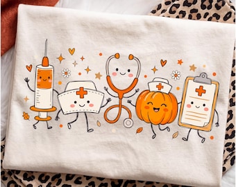 May include: An ivory t-shirt featuring a graphic print of cartoon medical items including a syringe, a nurse cap, a stethoscope, a pumpkin wearing a nurse cap, and a clipboard, all with smiling faces, surrounded by orange hearts, stars, and leaves.