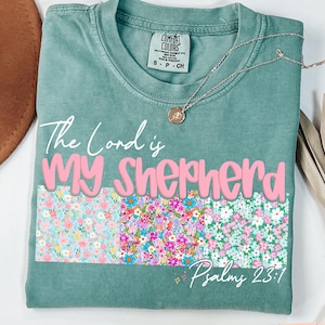 May include: A teal blue t-shirt with a floral print and the text "The Lord is My Shepherd, Psalms 23:1".