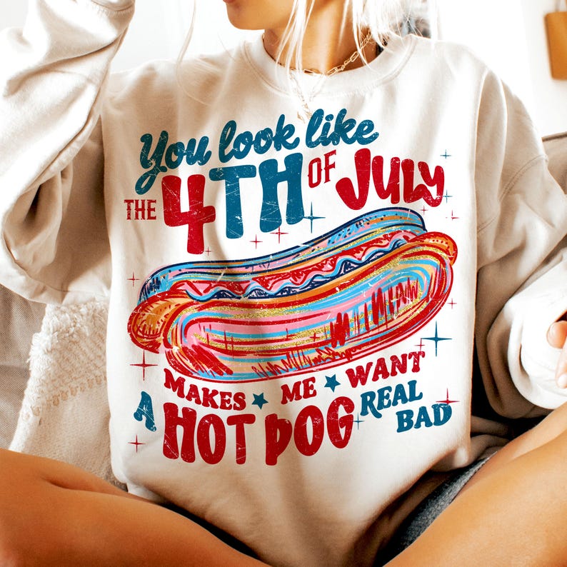 May include: Cream-colored sweatshirt with a colorful graphic of a hot dog and text that reads "You look like the 4th of July. Makes me want a hot dog real bad."