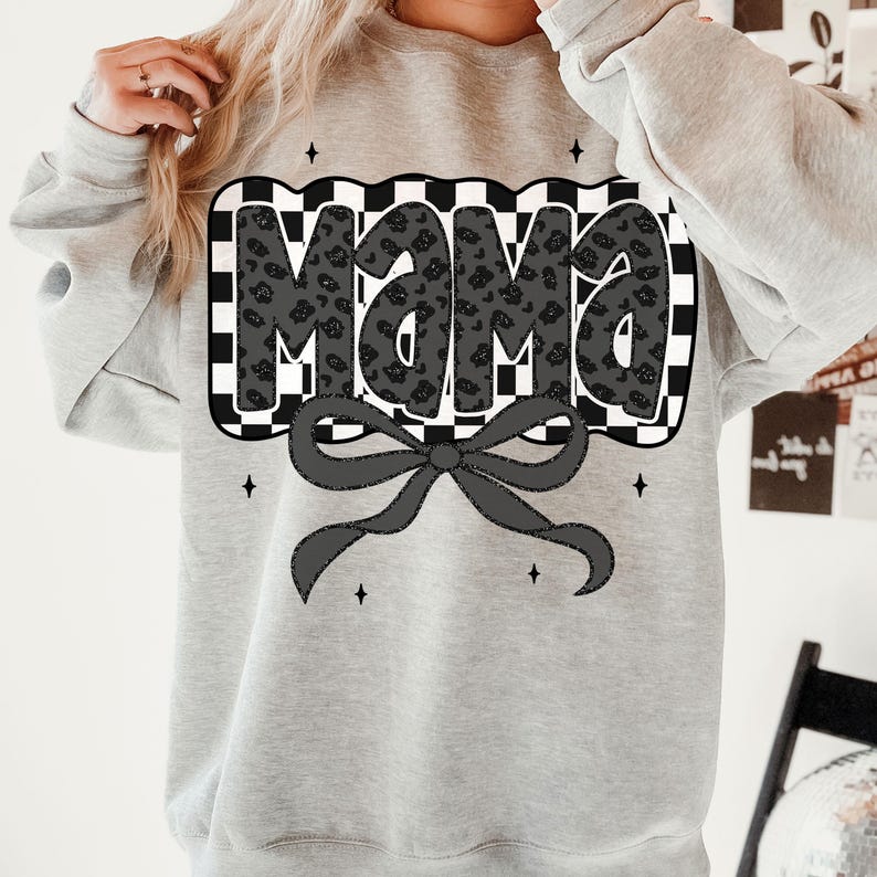 May include: A light gray sweatshirt featuring the word "Mama" in a black leopard print design, set against a black and white checkered background. A black bow is below the text, with small star accents.
