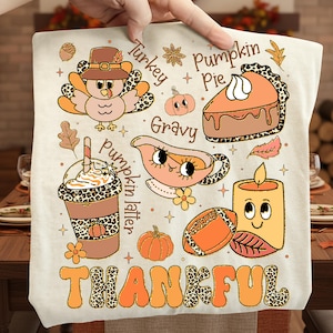 May include: A beige Thanksgiving-themed graphic with illustrations of a turkey, pumpkin pie, pumpkin spice latte, gravy boat, football, candle, and pumpkins. The word "THANKFUL" is written in large, orange letters with a leopard print pattern.