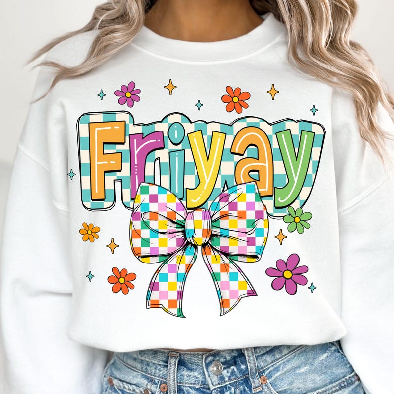 Peut inclure: Sweat-shirt blanc avec un motif &agrave; carreaux color&eacute;s qui dit "Friyay" avec un n&oelig;ud &agrave; carreaux arc-en-ciel. Le motif est entour&eacute; de petites fleurs et d'&eacute;toiles.