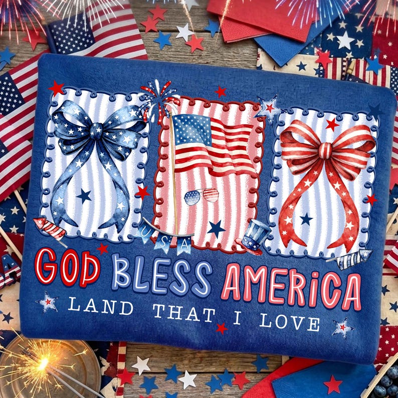 Puede incluir: Una sudadera azul con gr&aacute;ficos patri&oacute;ticos. El dise&ntilde;o incluye un lazo azul, una bandera estadounidense y un lazo rojo, todos enmarcados con un borde festoneado. El texto "GOD BLESS AMERICA" y "LAND THAT I LOVE" se muestra en rojo y azul.