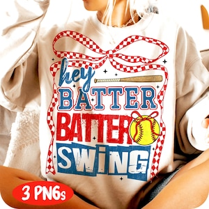 Könnte beinhalten: Ein weißer Pullover mit einer rot-weiß-blauen karierten Schleife und einem Baseballschläger-Motiv. Der Text "Hey Batter Batter Swing" ist auf dem Pullover aufgedruckt.