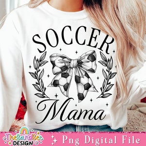 May include: Black and white graphic design of a soccer ball bow with leaves and stars. The text "Soccer Mama" is written below the bow.
