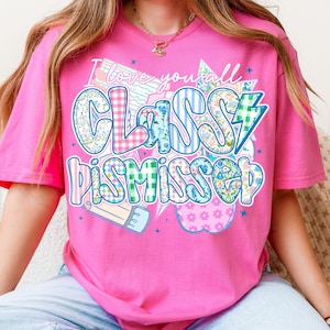May include: Pink t-shirt with a colorful graphic that says "I love you all Classy Dismissed". The graphic features a pencil, an apple, and stars.