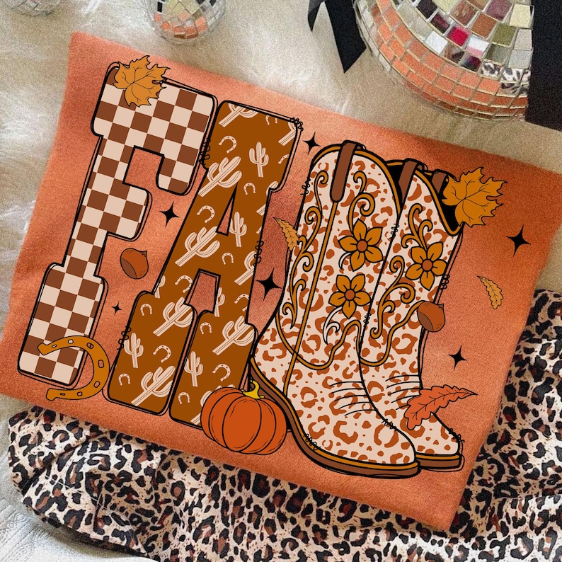 May include: Orange sweatshirt featuring the word "FALL". The "F" is a brown and white checkerboard pattern, the "A" has cacti and horseshoes, and the "LL" features cowboy boots with floral designs and a pumpkin. Autumn-themed apparel.