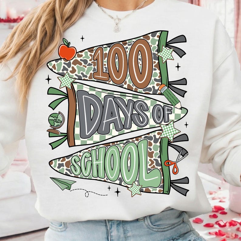 May include: White sweatshirt with a colorful graphic celebrating 100 days of school. The design features banners with the words "100 Days of School" in brown, gray, and green, along with school-themed illustrations like an apple, pencil, and globe.