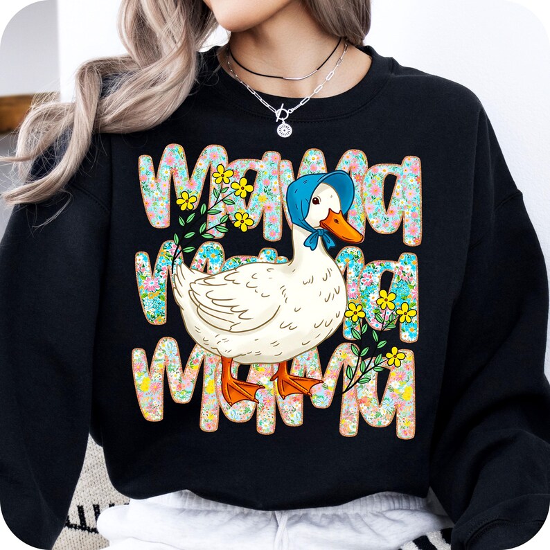 May include: Black sweatshirt featuring the word "MAMA" repeated three times in a floral design. A white duck wearing a blue bonnet is in the centre. The duck has an orange beak and feet. Yellow flowers and green leaves are also in the design.