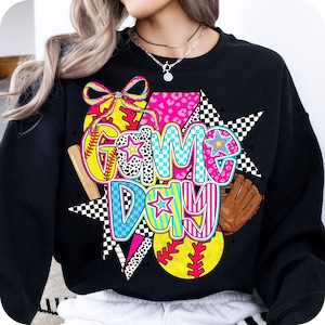May include: Black sweatshirt with a colorful graphic design featuring the words "Game Day" with baseballs, bats, and stars.