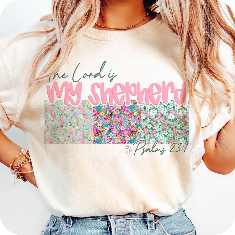 May include: A white t-shirt with a floral design and the text "The Lord is My Shepherd" in pink lettering. The text "Psalms 23:1" is also included in smaller lettering.