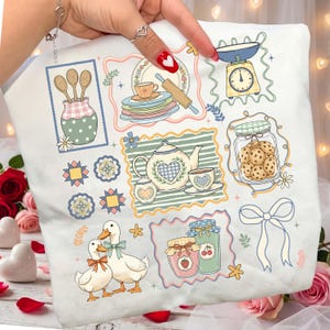 May include: White pillow with a charming kitchen-themed design. Features illustrations of kitchen tools, a teapot, ducks, cookies, and jars of jam. The design includes pastel colors and a vintage aesthetic, perfect for a cozy kitchen.