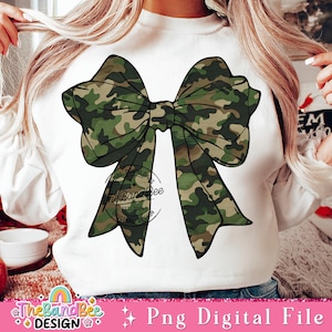 May include: A white sweatshirt with a large camouflage bow on the front. The bow is green and brown with a white background. The sweatshirt has the text "The Band Bee" in a circle on the front.