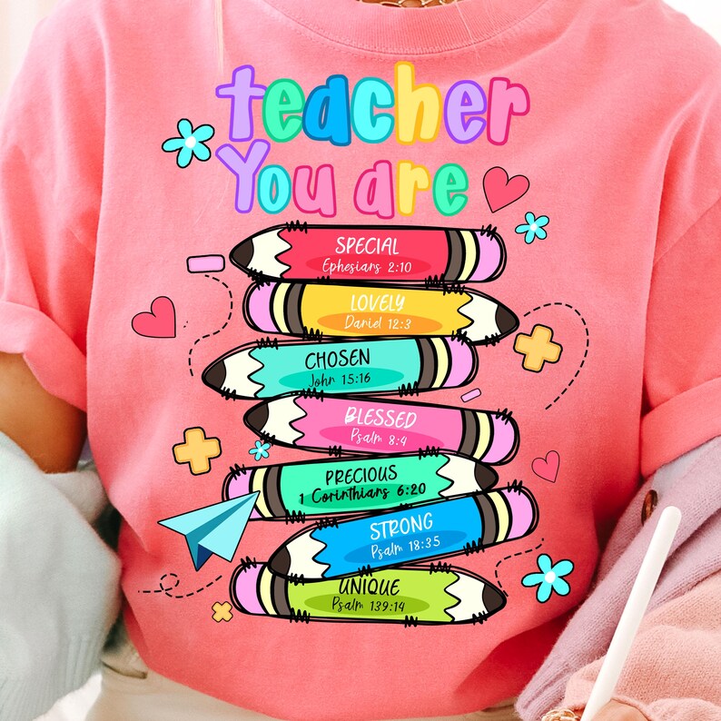 May include: Pink t-shirt with the words "teacher You are" in colorful letters. Below the text are stacked pencils with words like "Special," "Lovely," and "Chosen." Each pencil has a Bible verse reference. The design includes hearts, flowers, and a paper airplane.