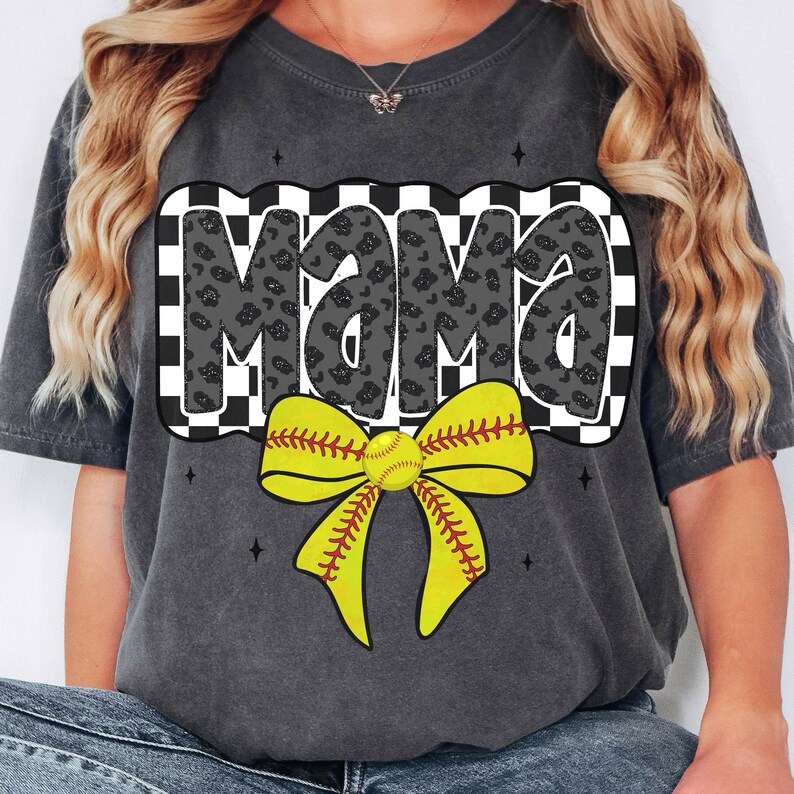Puede incluir: Una camiseta gris con un dise&ntilde;o a cuadros blanco y negro y la palabra "Mama" en negro con un estampado de leopardo. Un lazo amarillo de softball con detalles de costura roja y una pelota de softball est&aacute;n en el centro del dise&ntilde;o.