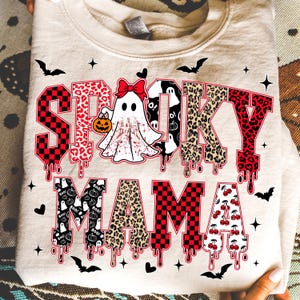May include: A beige sweatshirt with the words "Spooky Mama" in a mix of fonts and patterns. The word "Spooky" has a checkered pattern, leopard print, and dripping blood effect. A ghost with a bow and pumpkin is in the center. Bats and stars are scattered around.